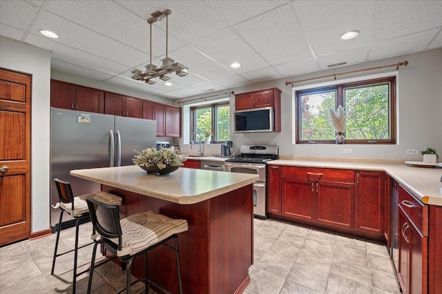 670 Leslie Ct, Carol Stream, IL 60188 - kitchen with stainless steel appliances, light countertops, a kitchen breakfast bar, dark brown cabinets, and a kitchen island