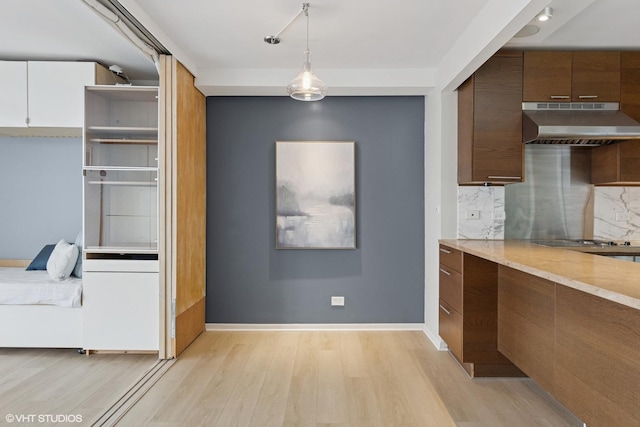 10 E Ontario St Unit 4805, Chicago, IL 60611 - kitchen featuring under cabinet range hood, light wood-style floors, tasteful backsplash, and pendant lighting