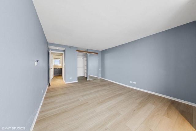 10 E Ontario St Unit 4805, Chicago, IL 60611 - unfurnished bedroom with a barn door, light wood-type flooring, baseboards, and a closet