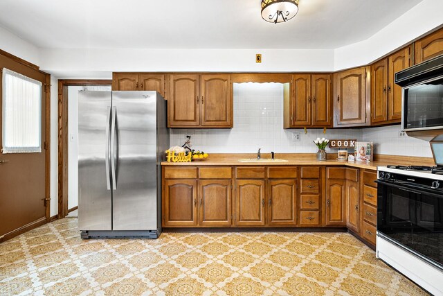 533 Lomond Dr, Mundelein, IL 60060 - kitchen with freestanding refrigerator, gas range oven, a sink, brown cabinetry, and light countertops