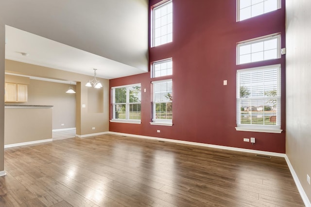 453 Lancaster Dr, Pingree Grove, IL 60140 - unfurnished living room featuring a chandelier, wood finished floors, a towering ceiling, and baseboards
