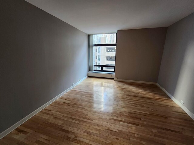 680 N Lake Shore Dr Unit 716, Chicago, IL 60611 - spare room featuring a baseboard heating unit, light wood-type flooring, and baseboards