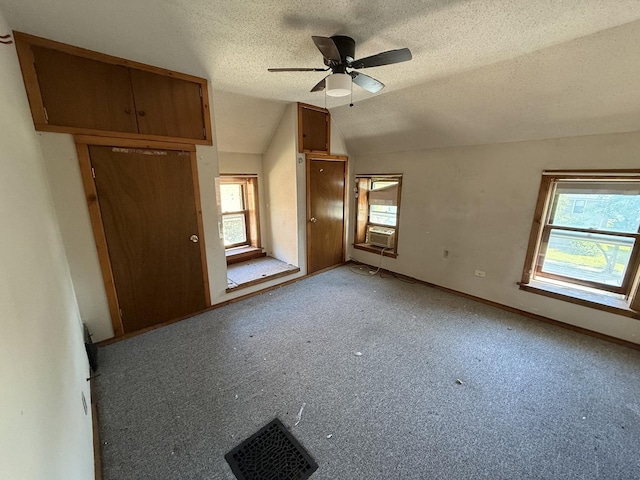 428 Chicago Ave, Savanna, IL 61074 - unfurnished bedroom featuring multiple windows, a textured ceiling, lofted ceiling, cooling unit, and baseboards