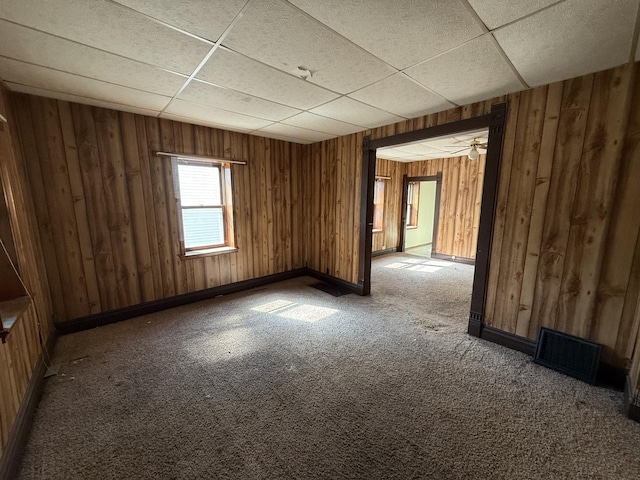 428 Chicago Ave, Savanna, IL 61074 - spare room featuring a paneled ceiling, wood walls, carpet, and baseboards