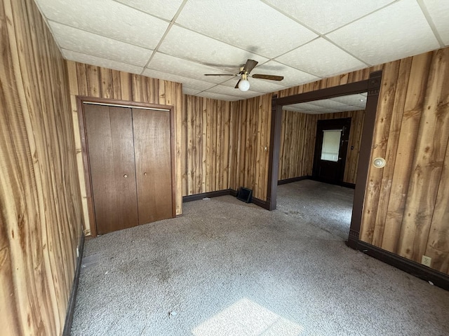 428 Chicago Ave, Savanna, IL 61074 - unfurnished bedroom with a drop ceiling, carpet floors, wood walls, ceiling fan, and a closet