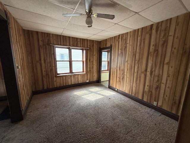 428 Chicago Ave, Savanna, IL 61074 - empty room with wooden walls, carpet floors, a paneled ceiling, ceiling fan, and baseboards