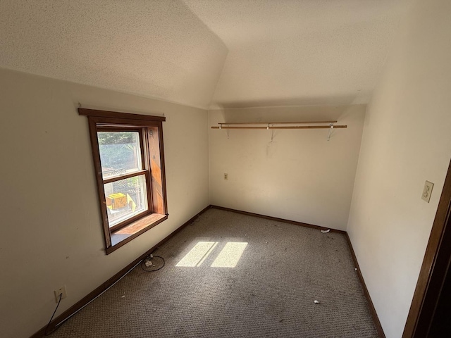 428 Chicago Ave, Savanna, IL 61074 - unfurnished bedroom with carpet, vaulted ceiling, a textured ceiling, and baseboards
