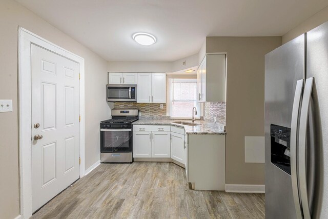 14746 Princeton Ave, Dolton, IL 60419 - kitchen featuring stainless steel appliances, a sink, light wood finished floors, white cabinets, and decorative backsplash