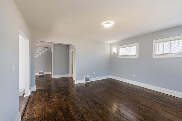 14446 Martin Luther King Jr Dr, Dolton, IL 60419 - empty room with arched walkways, dark wood-style floors, and baseboards