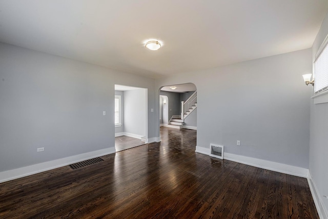 14446 Martin Luther King Jr Dr, Dolton, IL 60419 - spare room featuring arched walkways, dark wood-style floors, baseboards, and stairway