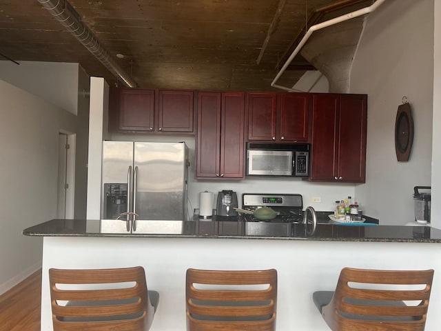 1001 W 15th St Unit 342, Chicago, IL 60608 - kitchen with appliances with stainless steel finishes, dark brown cabinets, a kitchen bar, wood finished floors, and dark stone countertops