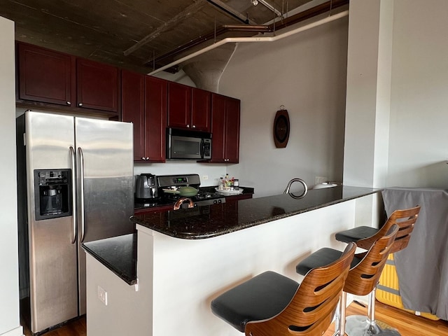 1001 W 15th St Unit 342, Chicago, IL 60608 - kitchen with appliances with stainless steel finishes, a peninsula, dark stone countertops, wood finished floors, and a breakfast bar area