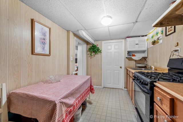 3324 N Ottawa Ave, Chicago, IL 60634 - kitchen with black gas range, extractor fan, wooden walls, and a paneled ceiling