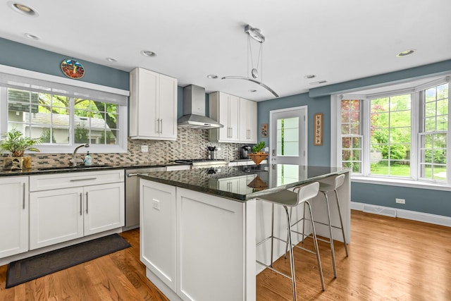 1101 Oak St, Winnetka, IL 60093 - kitchen featuring wall chimney range hood, a sink, light wood-style flooring, a kitchen bar, and decorative backsplash