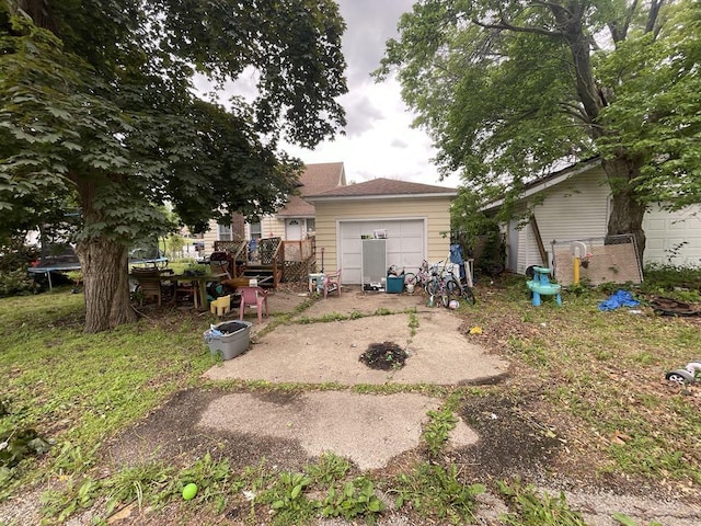 802 Locust St, Prophetstown, IL 61277 - rear view of property featuring a trampoline, a garage, and a wooden deck