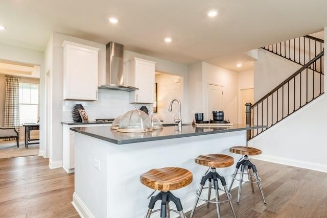 213 Rhinebeck Way, Algonquin, IL 60102 - kitchen with wall chimney range hood, an island with sink, white cabinetry, light wood-style floors, and recessed lighting