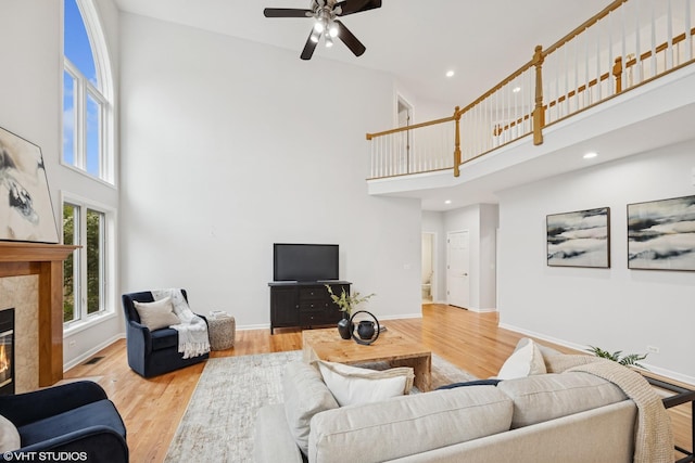 1040 E Buckingham Dr, Naperville, IL 60563 - living area featuring a towering ceiling, a tiled fireplace, ceiling fan, wood finished floors, and baseboards