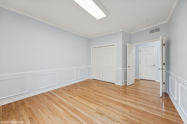 1040 E Buckingham Dr, Naperville, IL 60563 - unfurnished bedroom featuring ornamental molding, light wood-style floors, a wainscoted wall, a closet, and a decorative wall