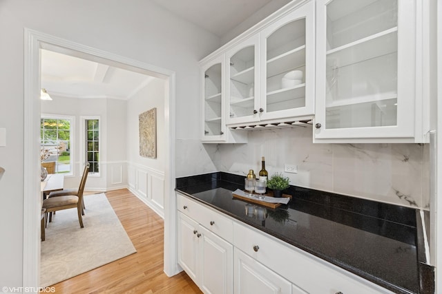 1040 E Buckingham Dr, Naperville, IL 60563 - kitchen featuring white cabinets, light wood-style flooring, glass insert cabinets, dark stone counters, and a wainscoted wall