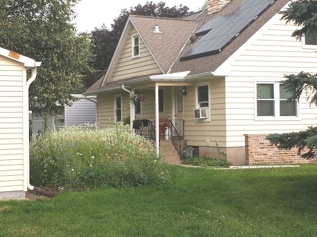 130 First St, Cary, IL 60013 - view of front of home featuring a shingled roof, a front yard, roof mounted solar panels, and a chimney