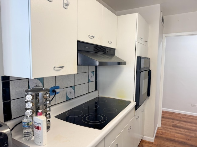 6301 N Sheridan Rd Unit 14E, Chicago, IL 60660 - kitchen with under cabinet range hood, black electric stovetop, backsplash, oven, and wood finished floors