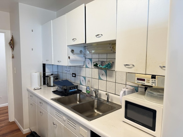 6301 N Sheridan Rd Unit 14E, Chicago, IL 60660 - kitchen with white microwave, a sink, decorative backsplash, and white cabinetry