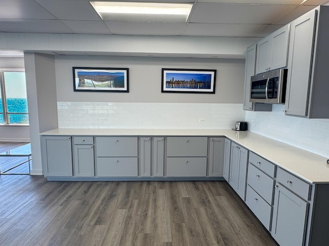 6301 N Sheridan Rd Unit 14E, Chicago, IL 60660 - kitchen featuring stainless steel microwave, gray cabinets, dark wood-style floors, decorative backsplash, and a paneled ceiling
