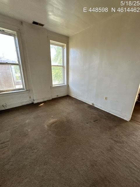 11739 S Indiana Ave, Chicago, IL 60628 - empty room with plenty of natural light, dark colored carpet, and baseboards