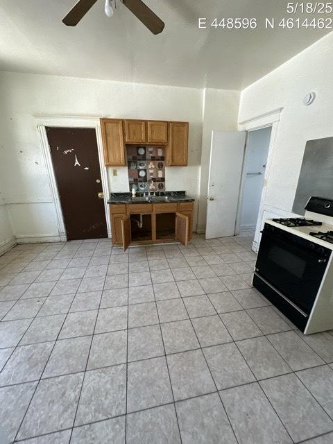 11739 S Indiana Ave, Chicago, IL 60628 - kitchen with range with gas stovetop, brown cabinets, ceiling fan, dark countertops, and light tile patterned flooring