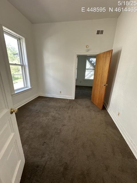 11739 S Indiana Ave, Chicago, IL 60628 - empty room featuring dark colored carpet, healthy amount of natural light, and baseboards