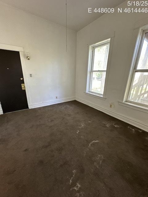 11739 S Indiana Ave, Chicago, IL 60628 - unfurnished room with dark carpet, plenty of natural light, baseboards, and vaulted ceiling