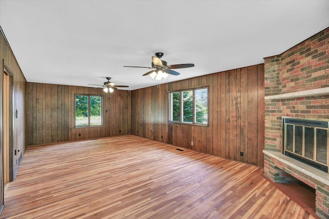 1651 Phillips Woods Ln, Urbana, IL 61802 - unfurnished living room featuring healthy amount of natural light, light wood-style floors, a brick fireplace, and wooden walls