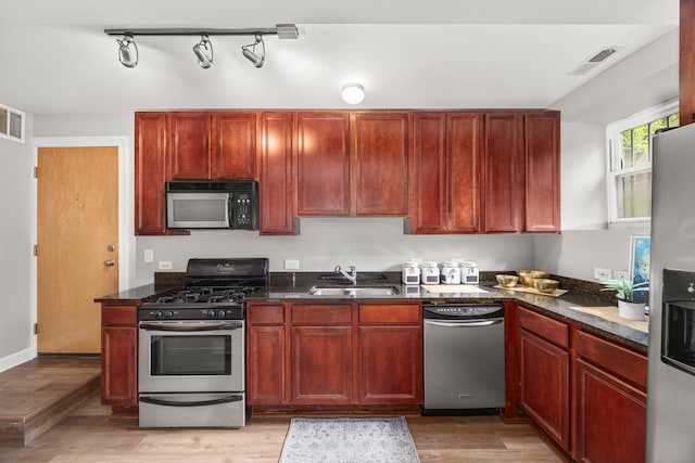 2316 W Cortez St Unit G, Chicago, IL 60622 - kitchen with stainless steel appliances, a sink, reddish brown cabinets, light wood-type flooring, and dark stone countertops