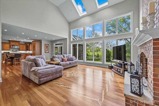 42W911 Jens Jensen Ln, Saint Charles, IL 60175 - living room featuring high vaulted ceiling, light wood finished floors, a skylight, a fireplace, and healthy amount of natural light