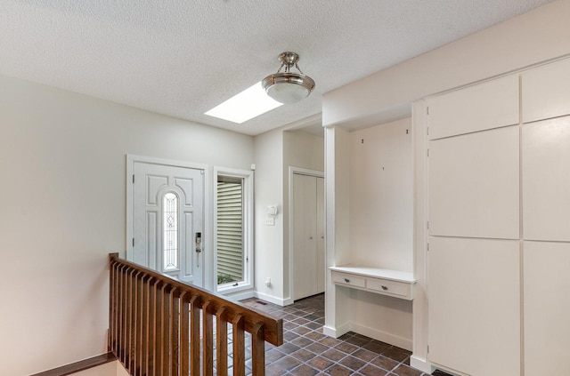 244 Greenwood N, Dekalb, IL 60115 - foyer featuring a skylight, dark tile patterned flooring, a textured ceiling, and baseboards