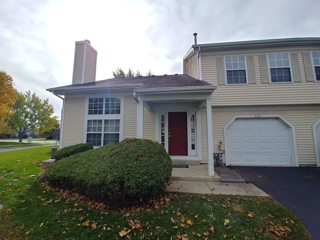 202 Teak Ln, Streamwood, IL 60107 - view of front of house with an attached garage, driveway, a chimney, and a front lawn