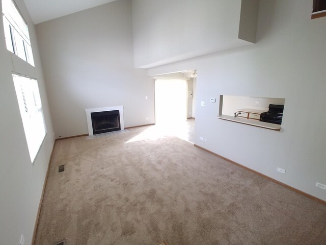 202 Teak Ln, Streamwood, IL 60107 - unfurnished living room with a high ceiling, carpet, a fireplace with flush hearth, and baseboards
