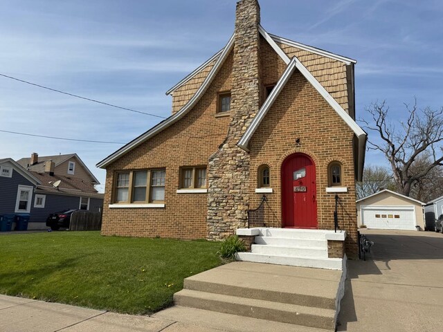 610 E Benton St, Aurora, IL 60505 - tudor home with a garage, an outdoor structure, a front yard, brick siding, and a chimney