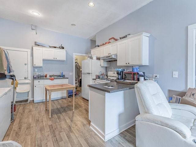 2823 W Flournoy St, Chicago, IL 60612 - kitchen with freestanding refrigerator, under cabinet range hood, a peninsula, stove, and white cabinets