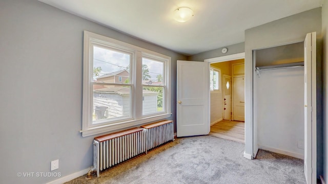7832 S Paxton Ave, Chicago, IL 60649 - unfurnished bedroom with radiator heating unit, a closet, and carpet