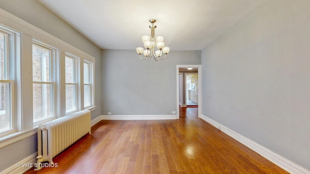 7832 S Paxton Ave, Chicago, IL 60649 - unfurnished room with radiator heating unit, wood finished floors, and a chandelier