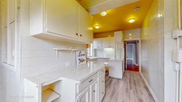 7832 S Paxton Ave, Chicago, IL 60649 - kitchen featuring light wood-style floors, white cabinets, tasteful backsplash, and tile walls