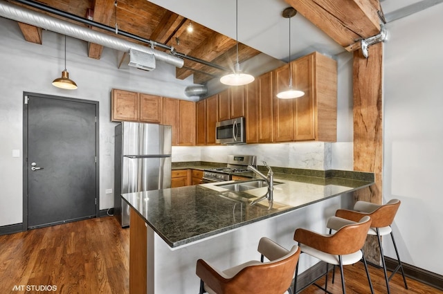 kitchen with stainless steel appliances, brown cabinets, a sink, dark wood finished floors, and wood ceiling with exposed beams
