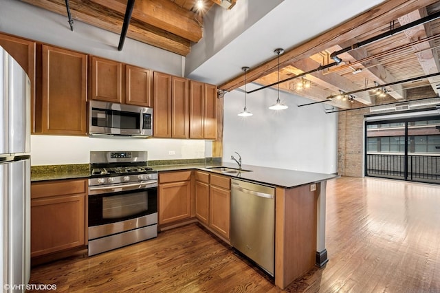 kitchen featuring stainless steel appliances, dark countertops, a sink, dark wood-style flooring, and beamed ceiling