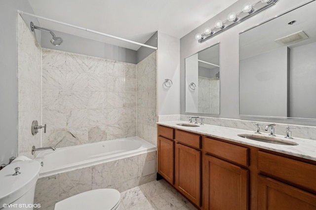 full bath with toilet, tiled shower / bath, and double vanity