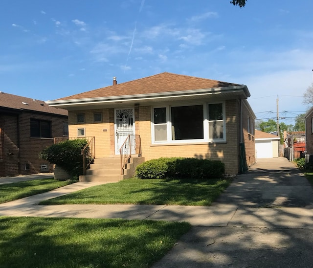 9833 S Marquette Ave, Chicago, IL 60617 - bungalow with brick siding, a front lawn, a garage, and an outbuilding