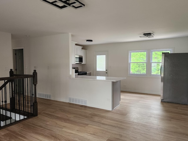 906 Central Park Dr, Round Lake Beach, IL 60073 - kitchen with appliances with stainless steel finishes, white cabinetry, light wood finished floors, and baseboards