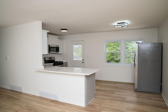 906 Central Park Dr, Round Lake Beach, IL 60073 - kitchen with appliances with stainless steel finishes, light countertops, white cabinets, and light wood-style floors