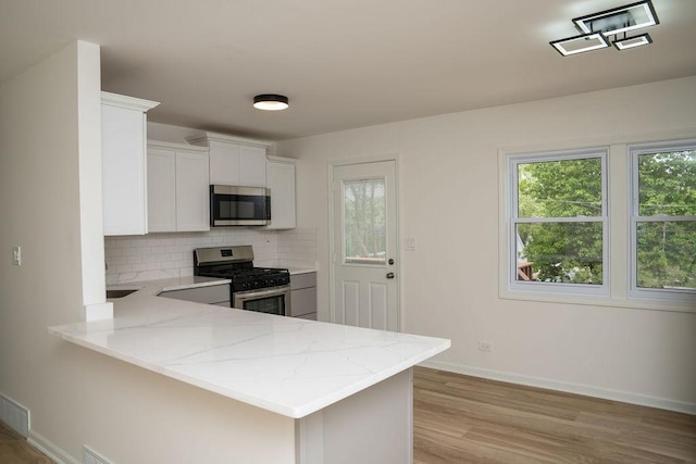 906 Central Park Dr, Round Lake Beach, IL 60073 - kitchen with appliances with stainless steel finishes, light stone counters, tasteful backsplash, baseboards, and light wood-style flooring