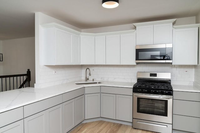 906 Central Park Dr, Round Lake Beach, IL 60073 - kitchen featuring stainless steel appliances, a sink, gray cabinetry, tasteful backsplash, and light stone counters